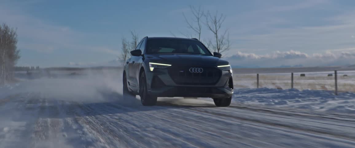 An audi vehicle drives along a rural snow dusted road