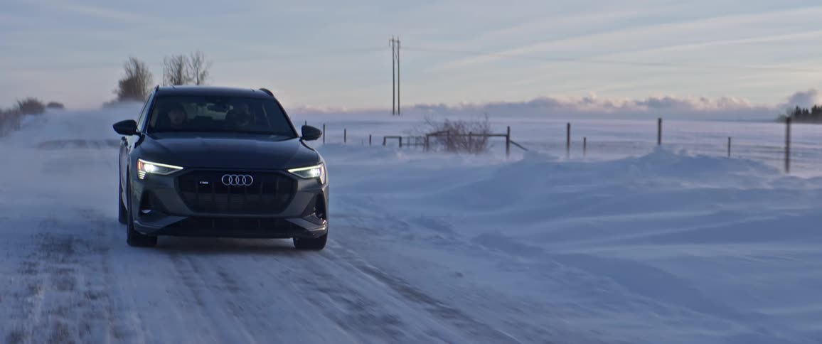 An audi car travels a rural snow covered road