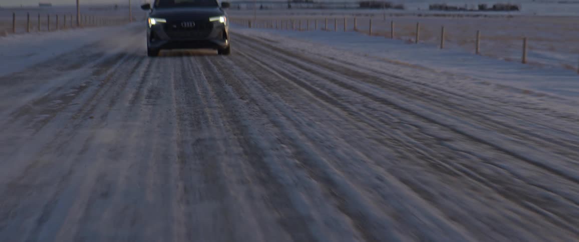 A view of a car driving down a road covered in snow
