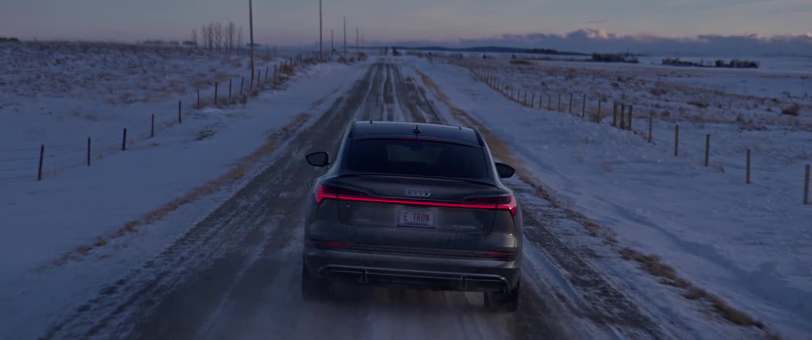 An audi vehicle travels a snow dusted rural road