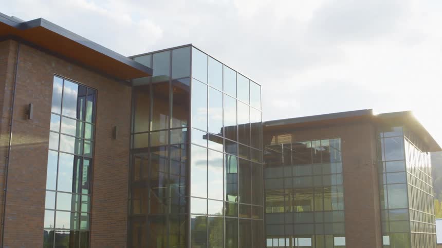Sunlight reflects and dances along the glass facade of a brand new corporate headquarters