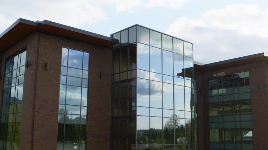 A new office building with cars reflecting in the windows as they drive by
