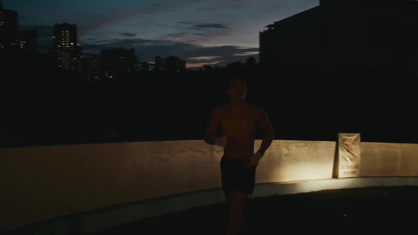 A man runs along a street as a vehicle follows behind him