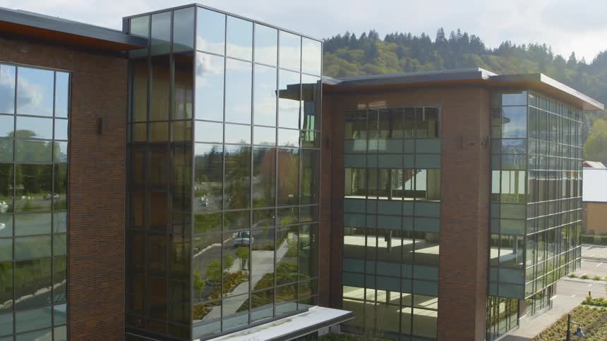 The sun and surroundings reflect from the windows of a new office building
