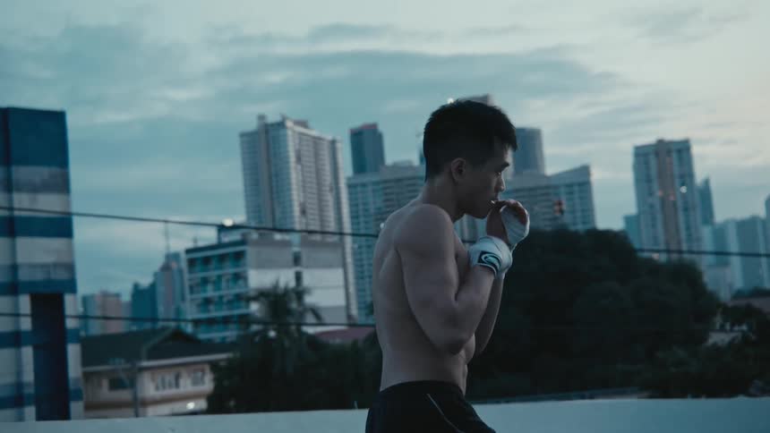 A man boxes on a rooftop with views of downtown