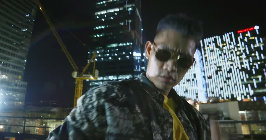 Dancer with sunglasses dancing on a rooftop with buildings in the background
