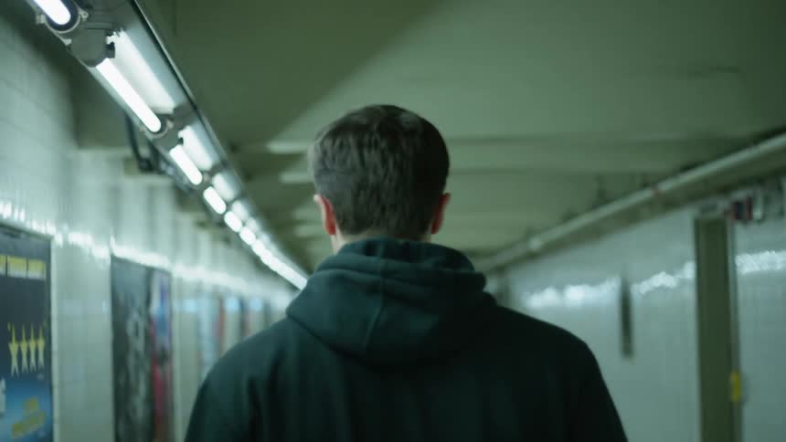 A man is walking quickly down the corridor of a subway station