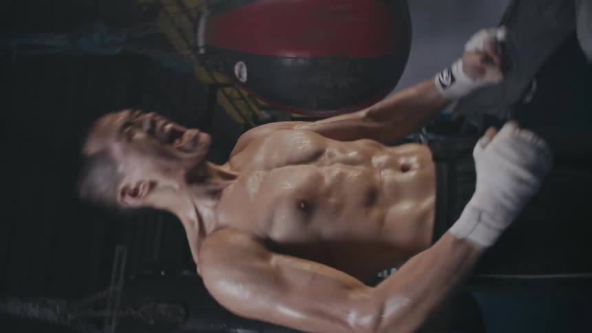 A man flexes his strength standing in a gym next to a punching bag