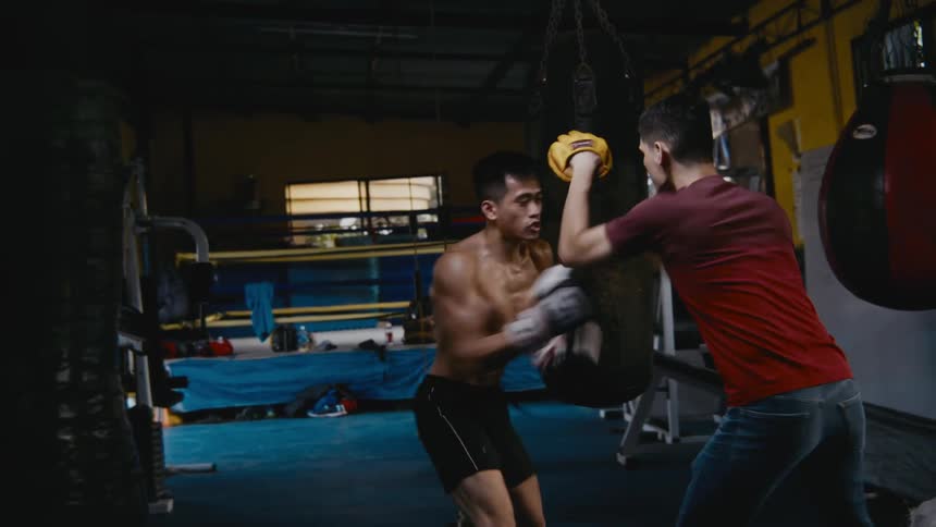 Two men are boxing together indoors