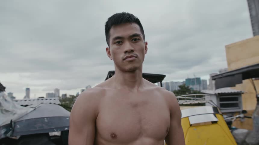 A man standing and staring with trees buildings the sky and clouds in the background
