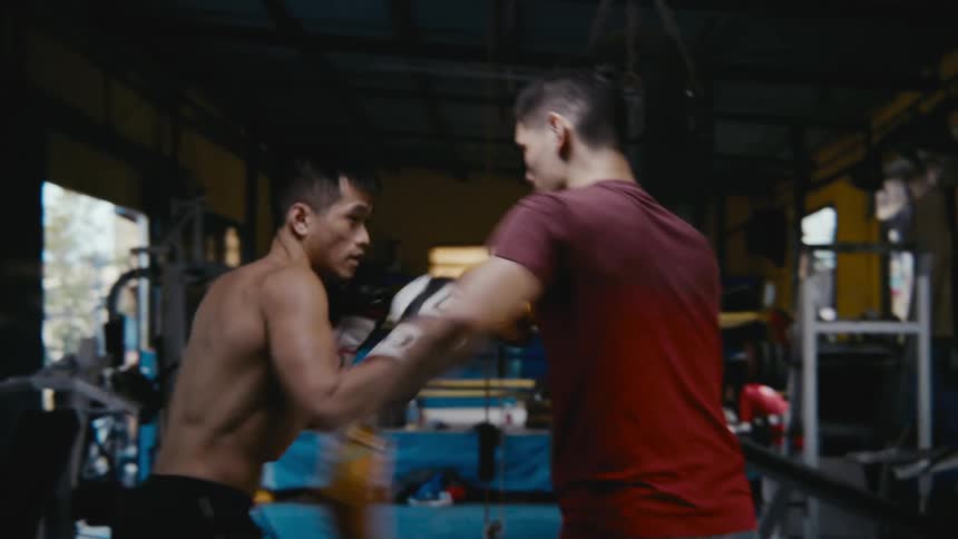 Boxer workout with trainer in gym with doorways leading outside