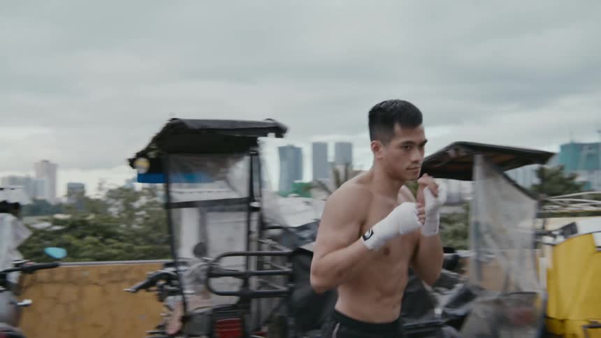 A man shadowboxing with trees buildings the sky and clouds in the background