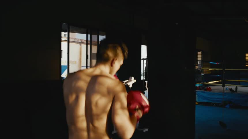 A male boxer punches a punching bag inside a gym