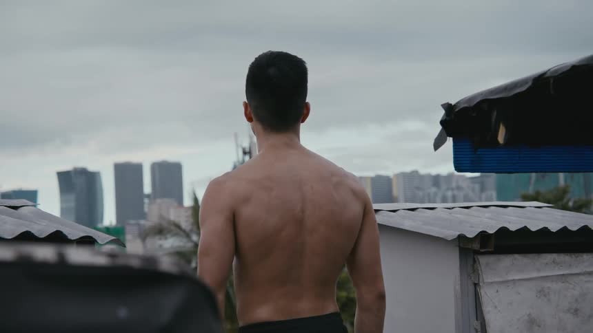 Strong muscular shirtless asian man looking at the city skyline