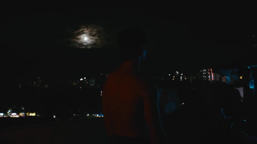 Strong muscular shirtless asian man standing near the city at night