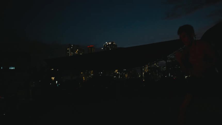 Young muscular shirtless man shadow boxing in front of the city skyline at night