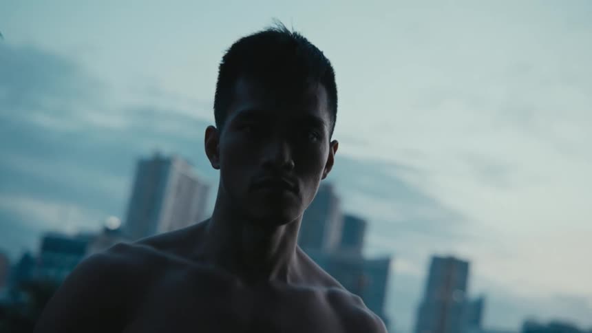 A man standing and staring with buildings skyscrapers the sky and clouds in the background
