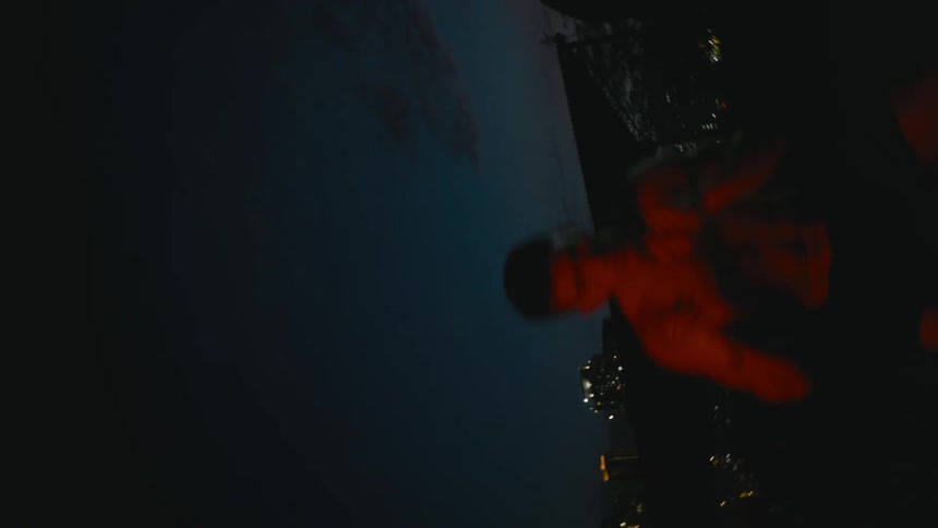 A man shadowboxing on a rooftop with buildings the sky and clouds in the background
