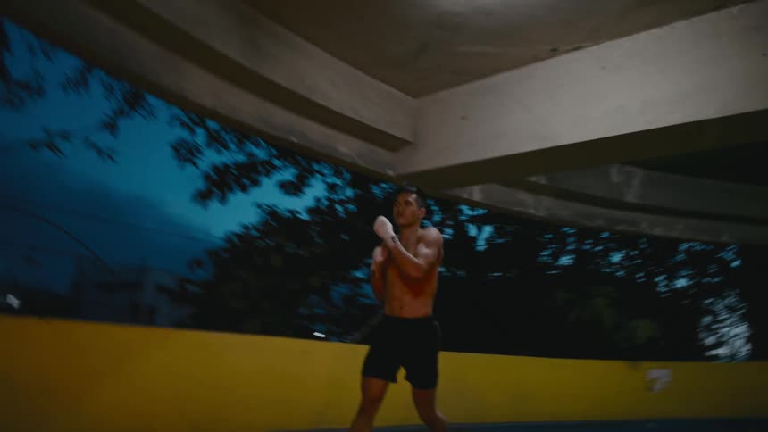 A man occasionally throws punches at the air as he jogs through a parking structure