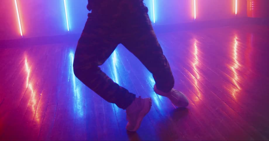 A man is dancing in front of the colorful lights