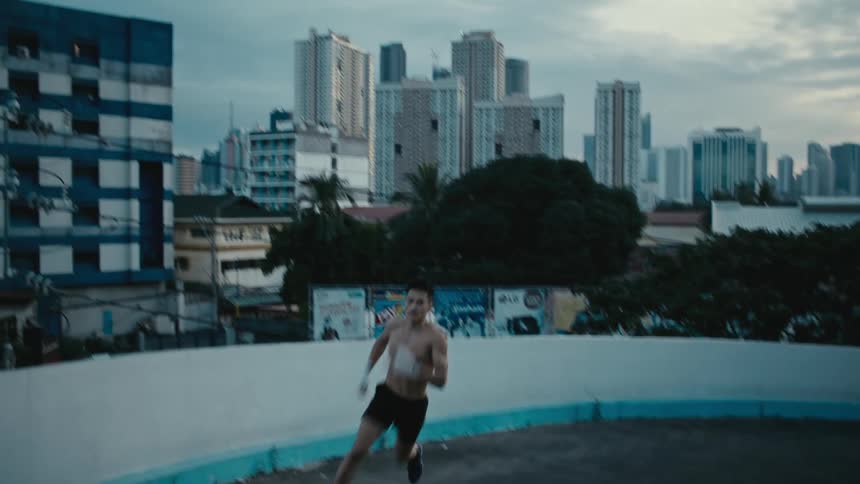 A man with shorts running with trees buildings the sky and clouds in the background