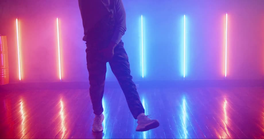 Young asian man dancing inside a room surrounded with colorful neon lights