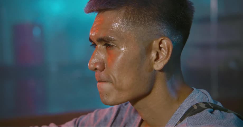 Man sitting on the floor of a dance studio with sweat on his face