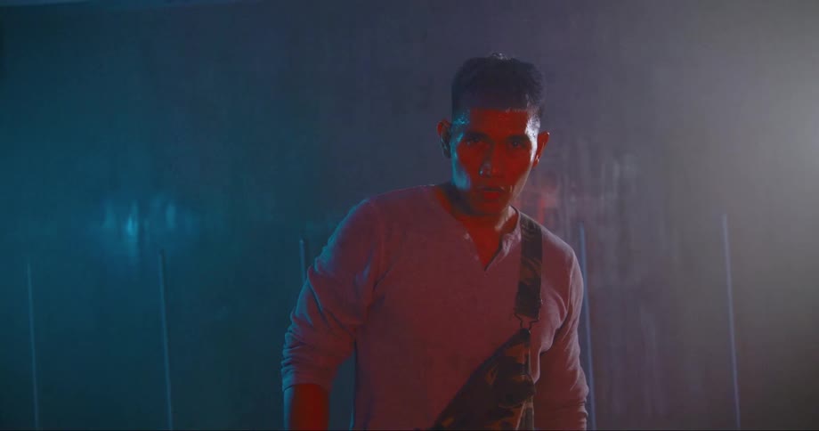 A man in a room staring with a wall in the background
