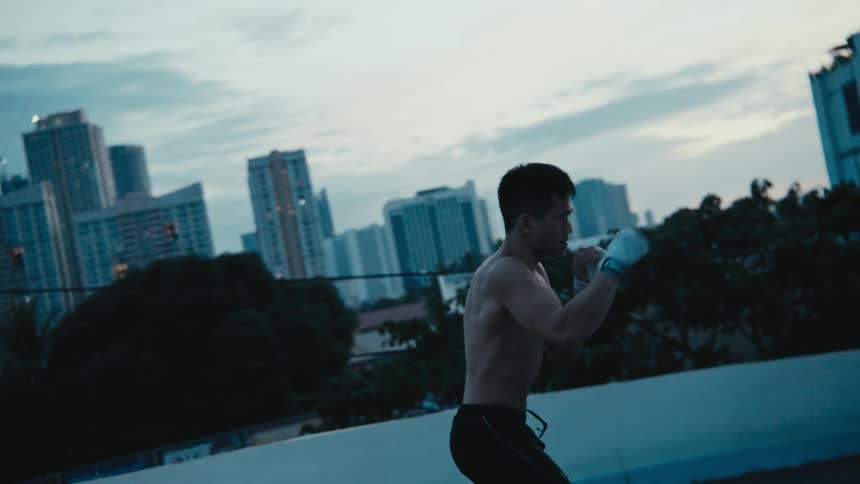 A man practices boxing moves in front of a city skyline
