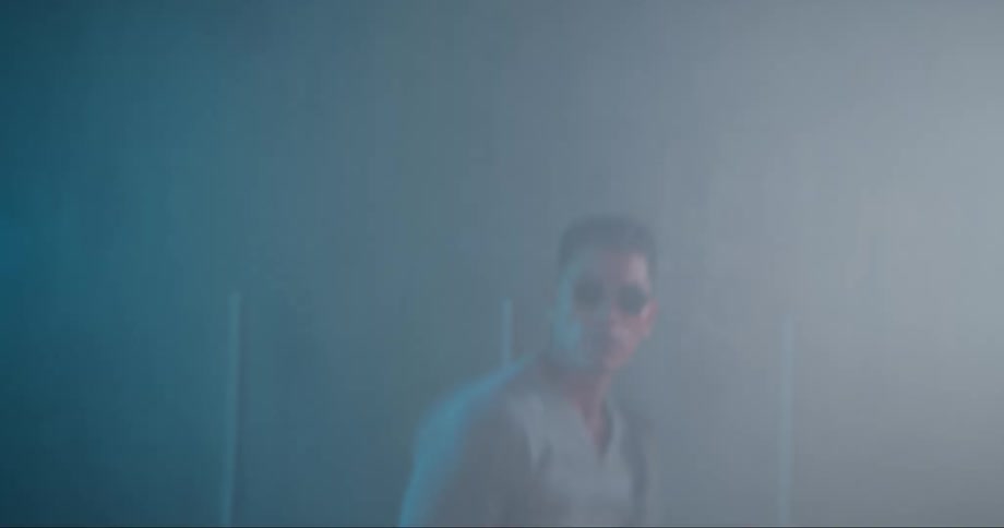 Young asian man wearing sunglasses dancing inside a room filled with smoke