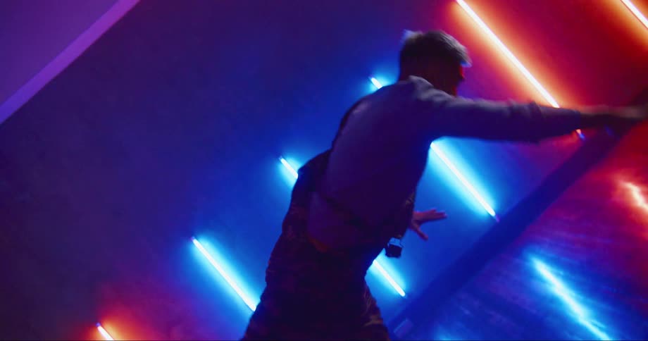 Young asian man dancing inside a room surrounded with colorful lights