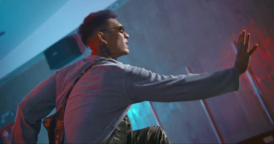 A man is dancing inside a room and wearing sunglasses