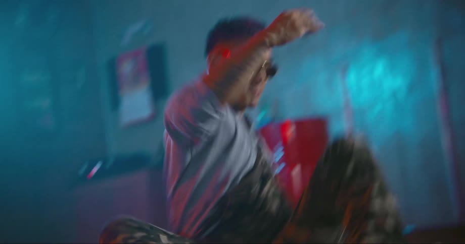 Young asian man wearing sunglasses dancing inside a room filled with smoke