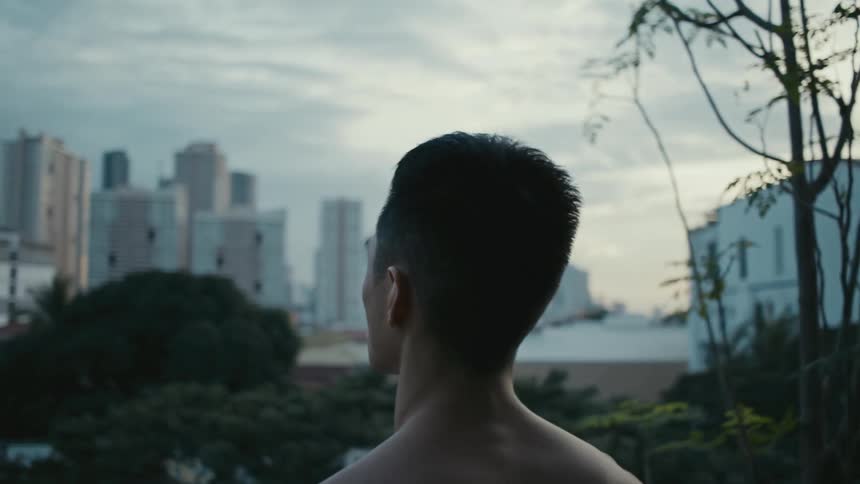 A man standing with trees buildings the sky and clouds in the background