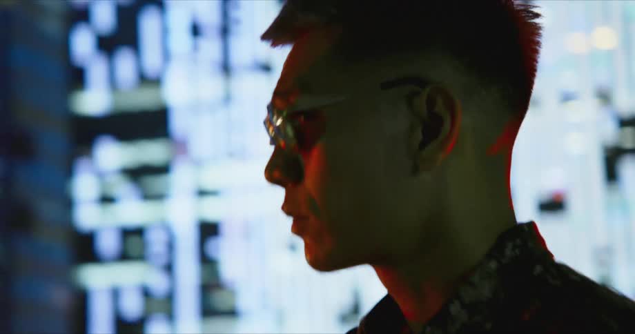 A man sways left and right as he walks into a nightclub with a digital display wall