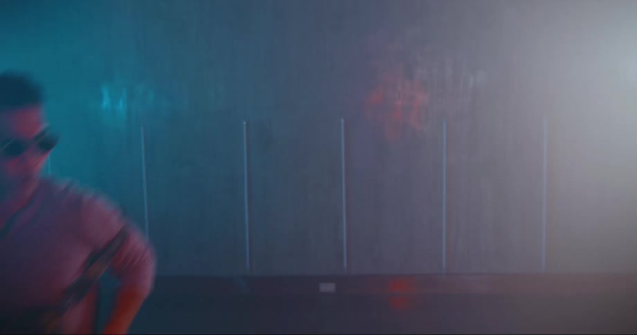 A man in sunglasses dances in a dimly lit room
