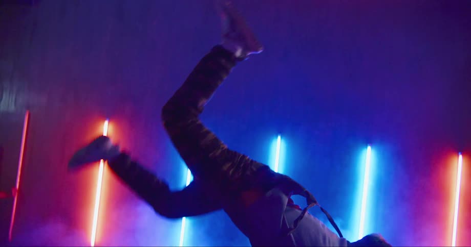 Young asian man dancing inside a room surrounded with colorful neon lights