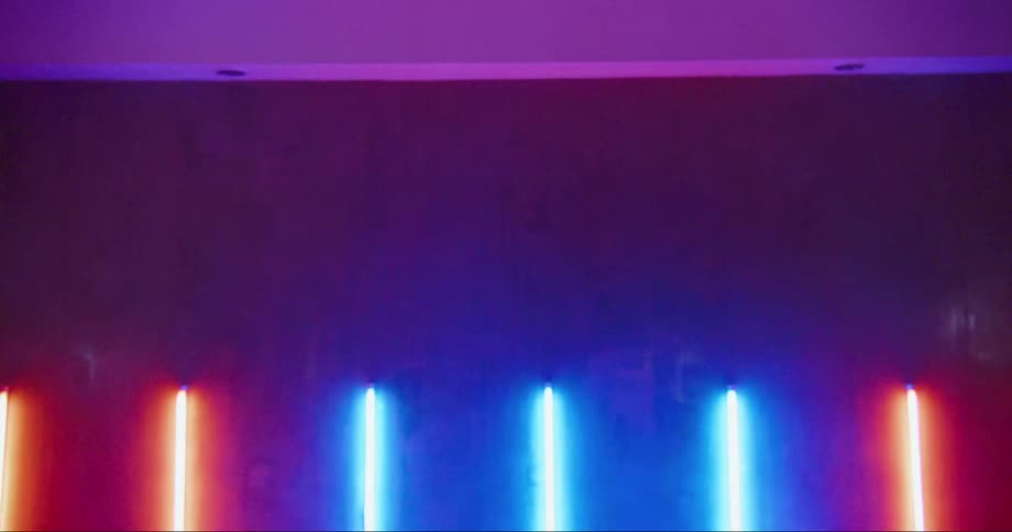 Young asian man dancing inside a room surrounded with colorful neon lights