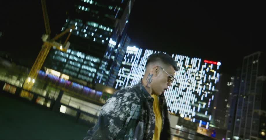 Dancer wearing sunglasses dances in front of the buildings in the city at night