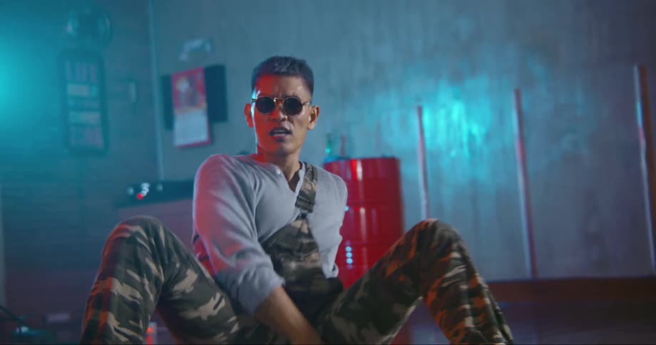 A man with sunglasses in a room dancing with a wall and a light in the background
