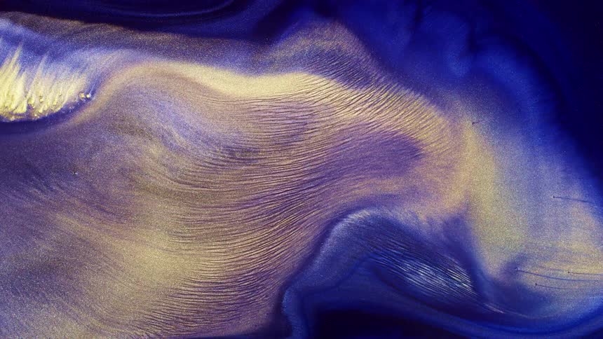 A yellow particular fluid sweeps its way through a rich blue and purple liquid