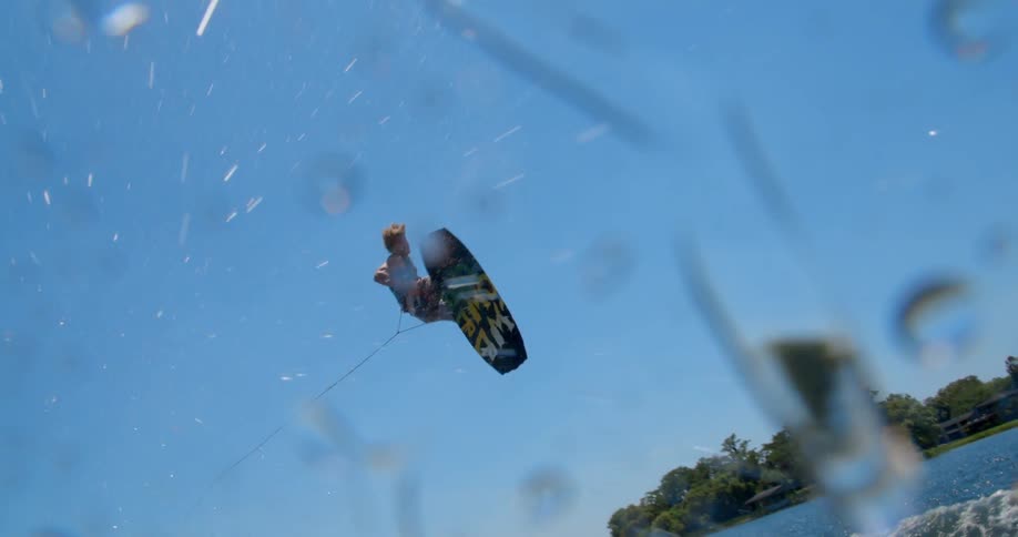 Water skier jumps and spins over a lake at daytime