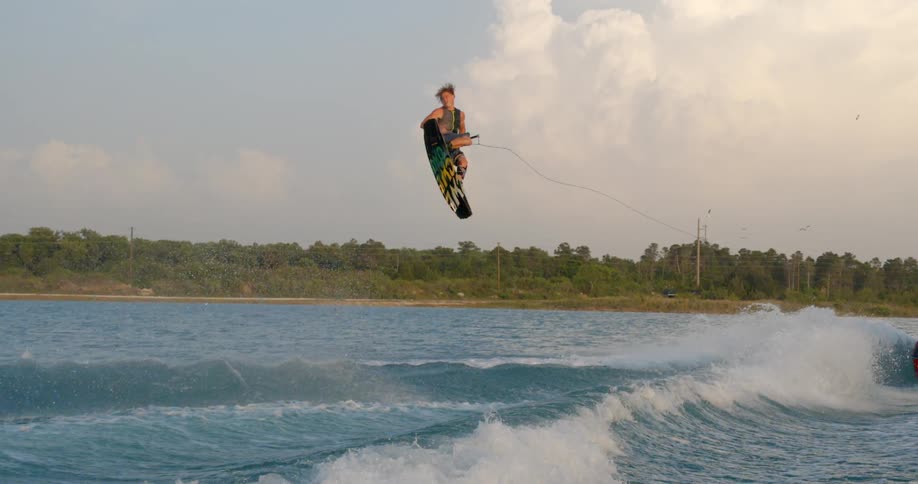 A man being towed by a motorboat performs an impressive jump on his wake board