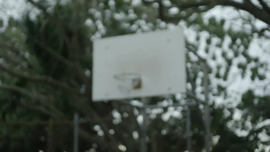 Man with braids and grey t shirt shoots a basketball in the basketball court