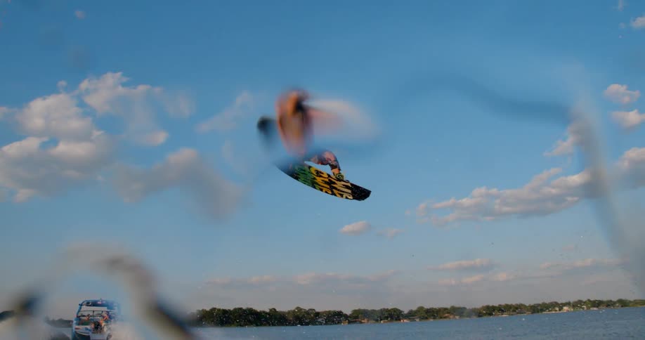 A young man makes a 360 degree spin on his surfboard while he is in the air