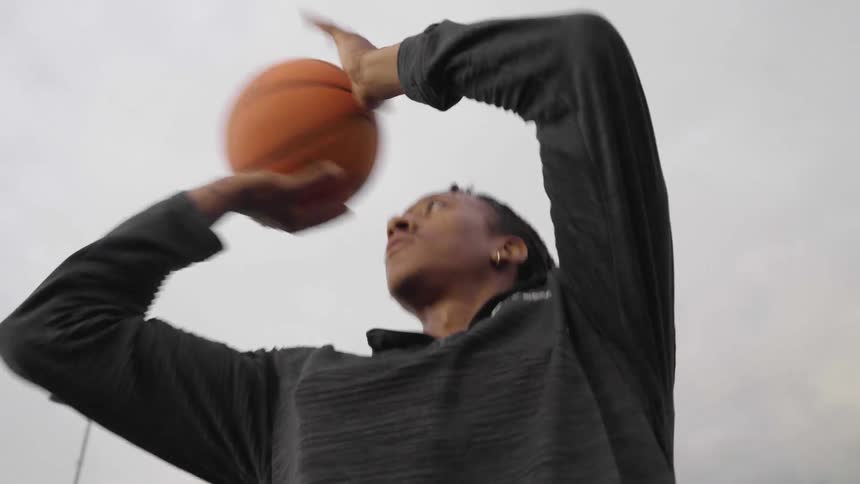 A young male basketball player preforms a ball fake and then shoots