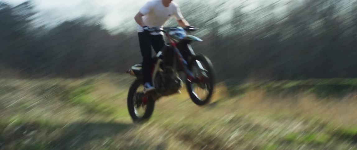 A man rides motocross over jumps in a field