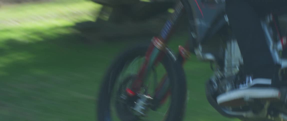 A person driving a motorcycle in a forest with grass and trees