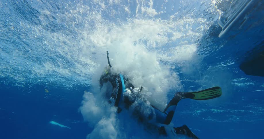 A diver jumps off a boat in to the ocean