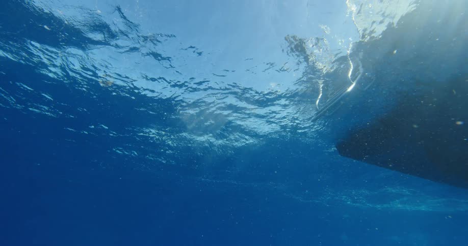 Underwater with bubbles in the ocean with a boat with a ladder above